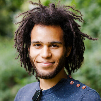 A man with dreadlocks is smiling for the camera.