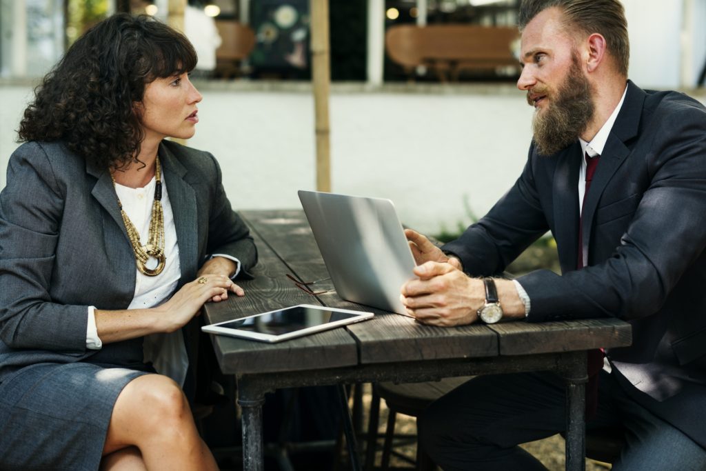 Business meeting at outdoor table with laptops.