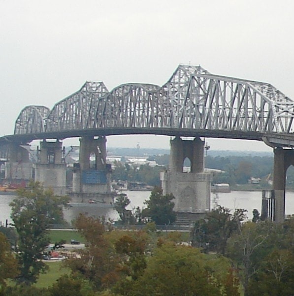 A large steel truss bridge over a river with boats underneath.